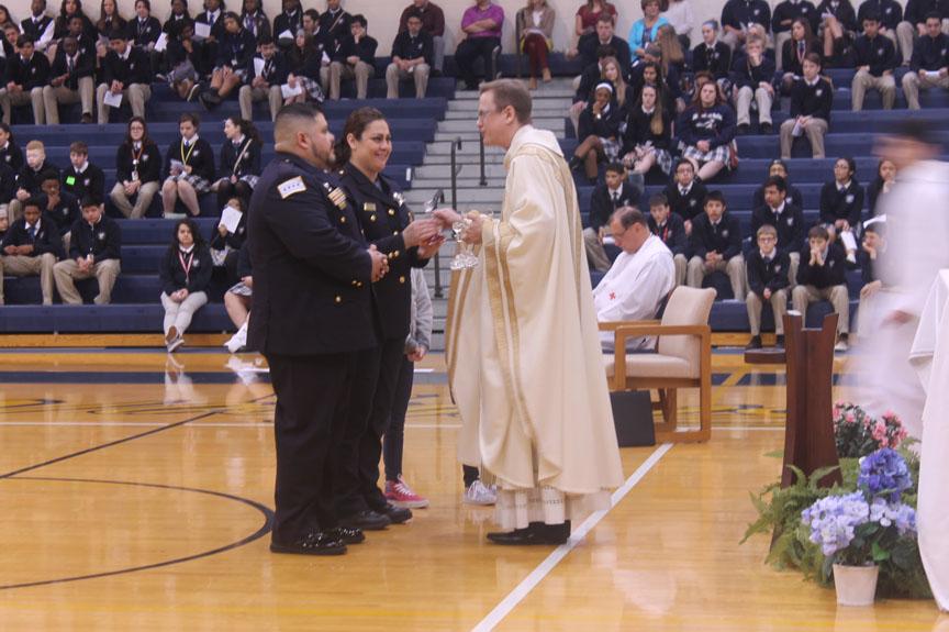 Carlos and Guadalupe Sanchez, parents of sophomore Carly Sanchez and Chicago police officers, bring Fr. Kevin Scalf, campus chaplain the gifts.