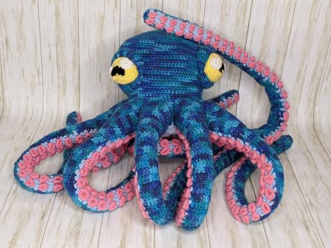 Blue octopus with pink suction cups and yellow eyes, entirely crocheted.